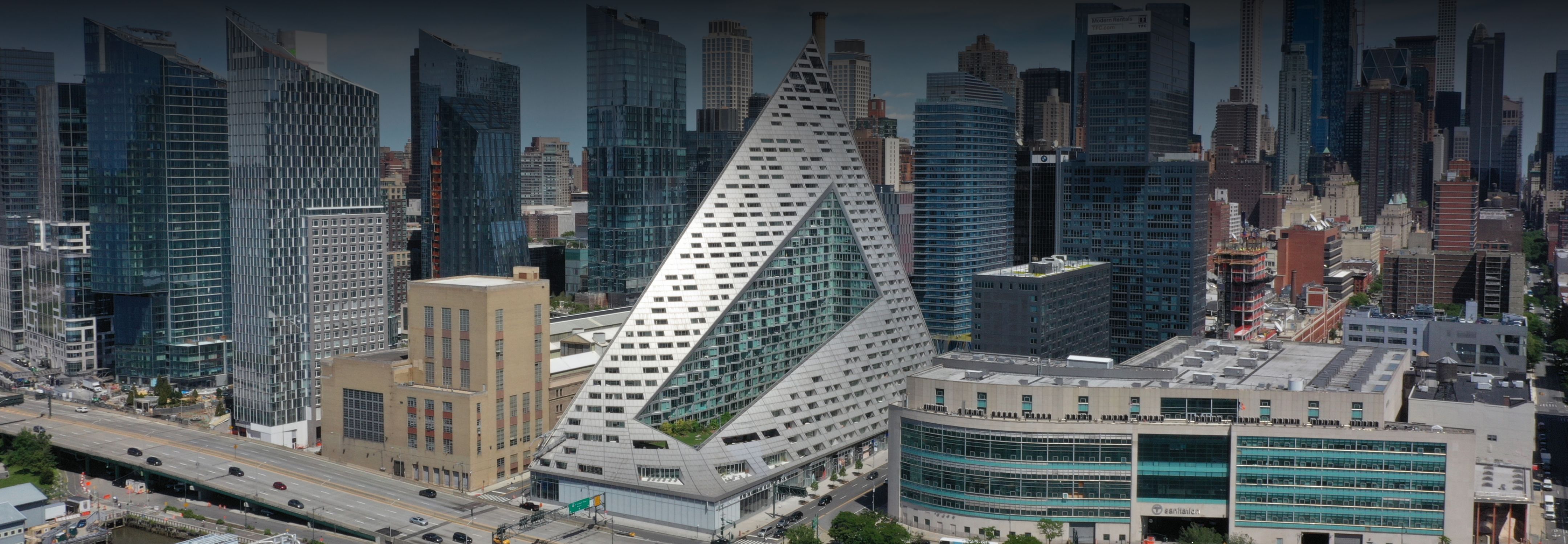 Aerial view of a city with the unique white pyramid-shaped VIA 57 WEST building among various modern high-rises.