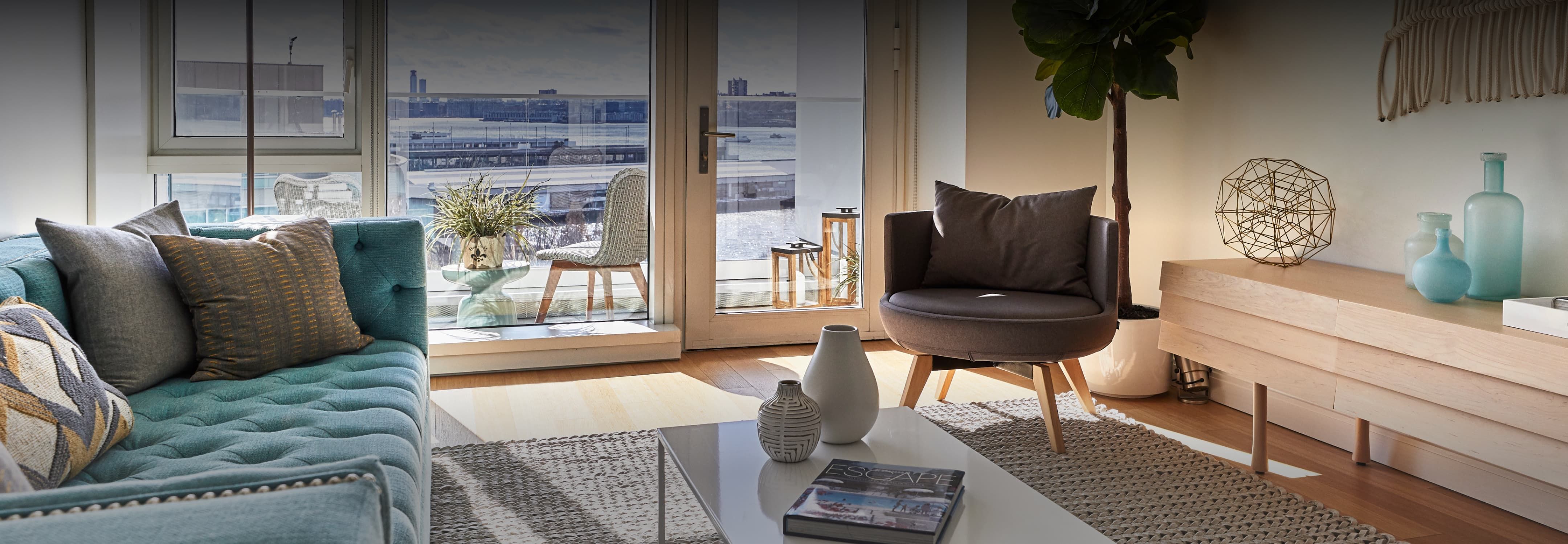 Inviting living room with large windows, teal sofa, eclectic decorations, and city view.