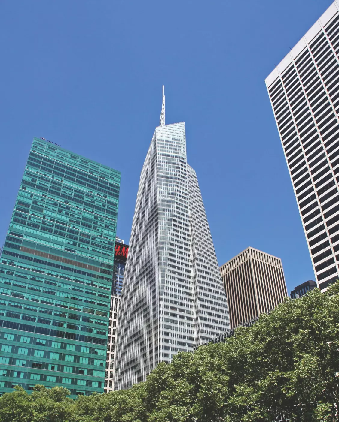 Cityscape with greenery, showcasing tall buildings under a clear blue sky.